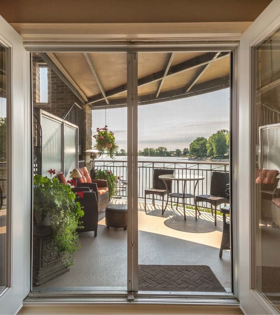 This picture is taken from inside a home and is looking through patio doors onto the patio. It features beautiful, white french doors. Pane Free Glass in Manchester, NH, can turn this dream into a reality for you in your home.
